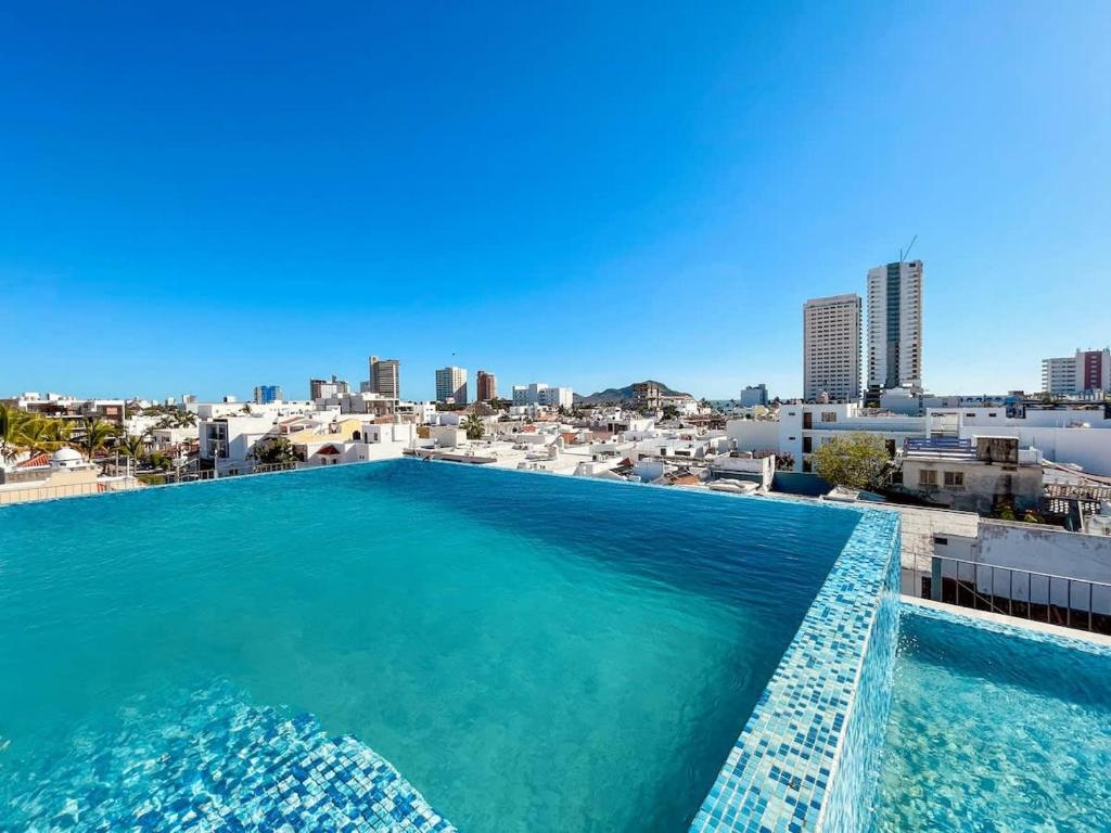 Apartment for 7 people with pool on the 3rd floor في Isla Venados: حمام سباحة على سطح مبنى مع مدينة في الخلفية