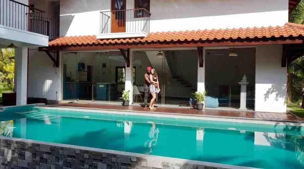 a woman is standing next to a swimming pool at Forest Avenue - Kurunegala in Torayaya