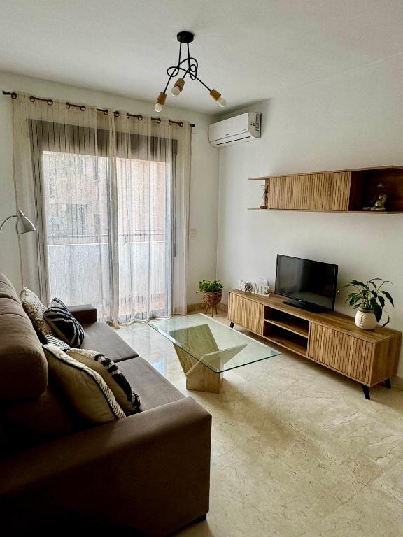 a living room with a couch and a television at Apartamento a 10 minutos de Granada, Sierra Nevada a 35km, parking gratis in Alhendín