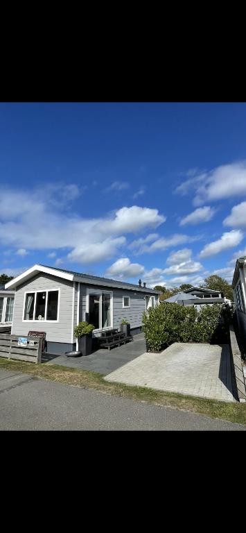 a white house with a porch on a street at Chalet Home Texel in De Koog