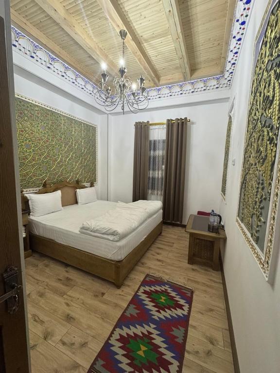 ein Schlafzimmer mit einem Bett mit einem Kronleuchter und einem Teppich in der Unterkunft Central asia hotel in Muruntau