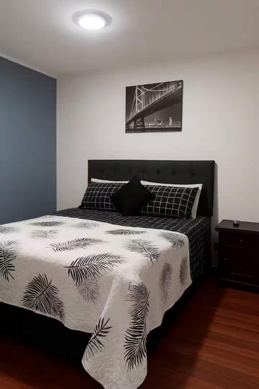 une chambre avec un lit avec une couverture noire et blanche dans l'établissement Departamentos Merced, à Santiago