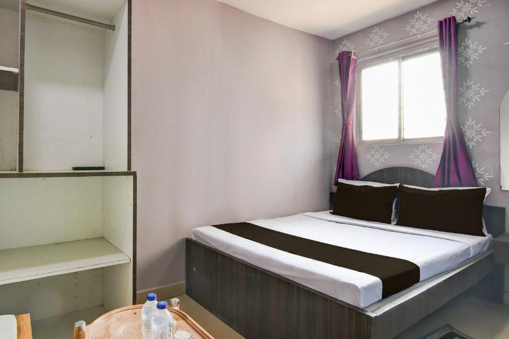 a bedroom with a bed with purple curtains and a window at Hotel O Sharan Guest House in Calcutta Bara Bazar