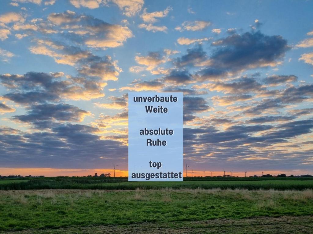 a sign in the middle of a field with a sky at Ferienhaus Robbenglück in Tossens - Ihr gemütliches Zuhause an der Nordsee in Butjadingen OT Tossens