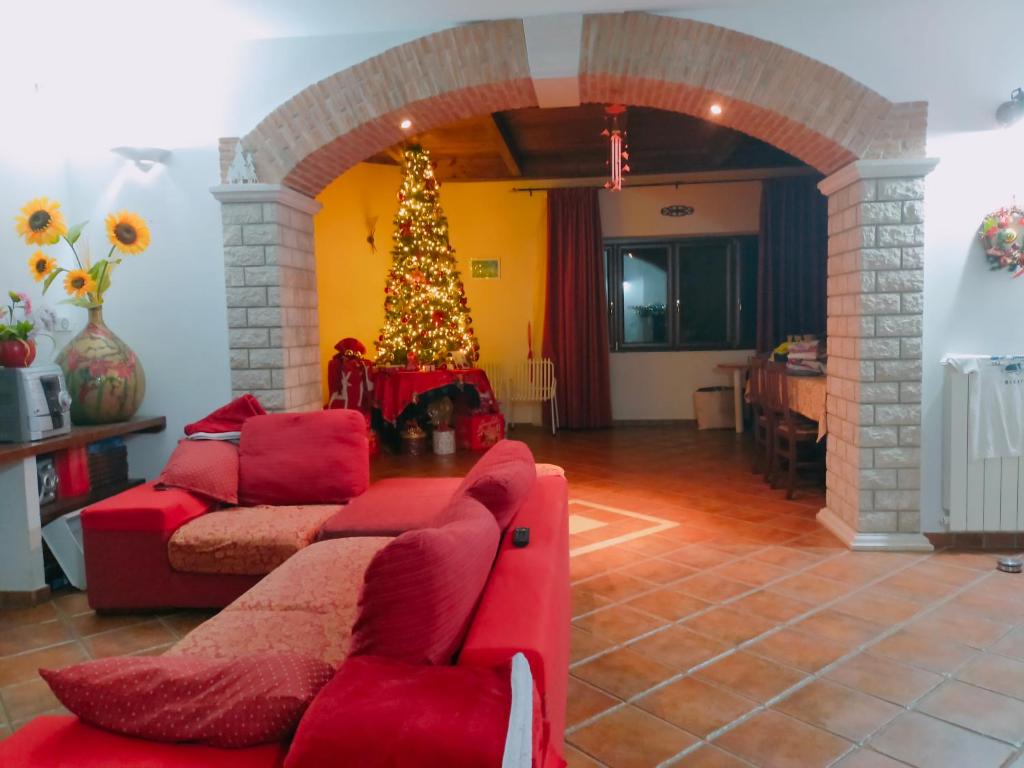a living room with a christmas tree and a red couch at Al Boschetto in Melizzano