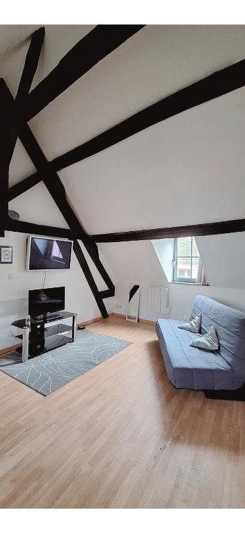 a living room with a blue couch and a tv at L'Envolée Mansardée - Center in Chartres