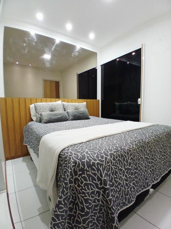 a bedroom with a bed with a black and white comforter at Apart 3qtrs á 1200m da praia de Itapuã in Vila Velha
