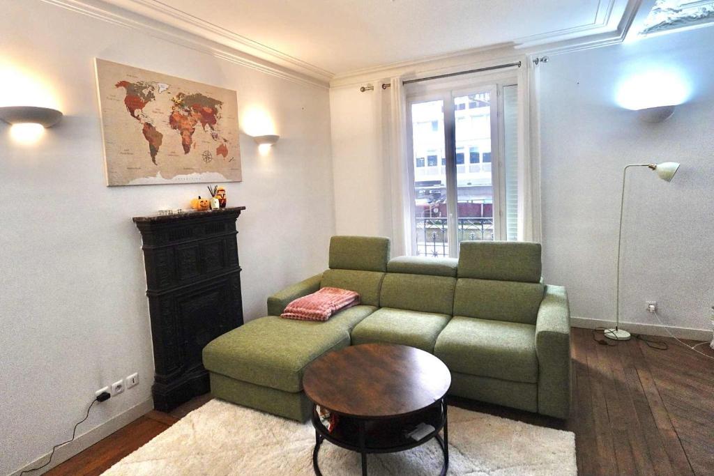 a living room with a green couch and a table at Comfort Parisian Room and Sofa Bed 1 min to Metro M4 & T3A in Paris