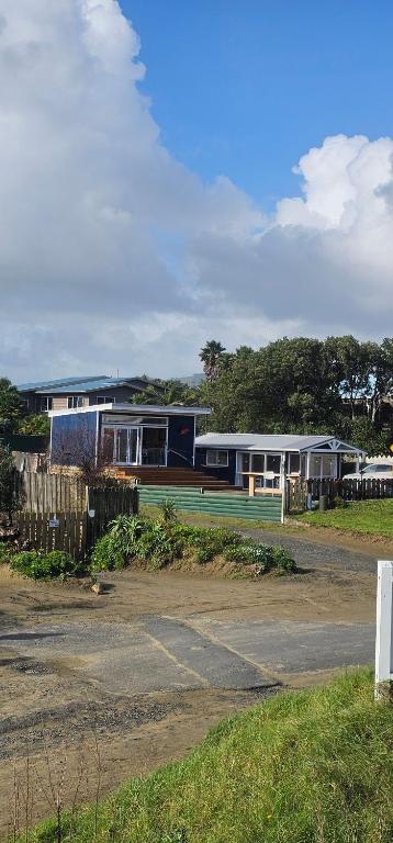 a building with a tennis court in front of it at Kiwi Bach - Beachfront & Sunsets in Ahipara