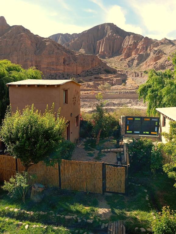 a house with a fence and mountains in the background at Los Amarantos in Tilcara