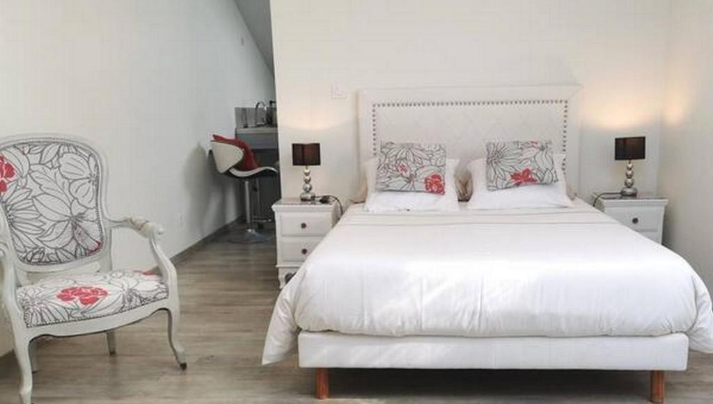 une chambre avec un lit blanc et une chaise dans l'établissement Studios MISTRAL21 en Camargue, à Salin-de-Giraud