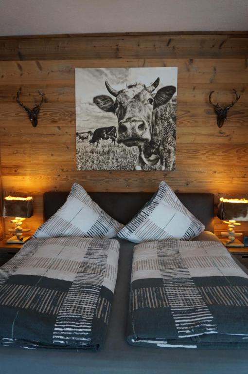 two beds with a picture of a cow on the wall at Wohlfühlstudio Bergblick in Walchsee in Walchsee