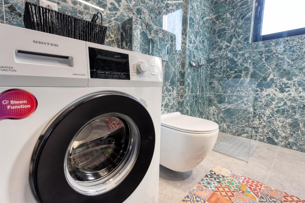 une machine à laver dans une salle de bain avec toilettes dans l'établissement V P Trikala Luxury Suites, à Tríkala