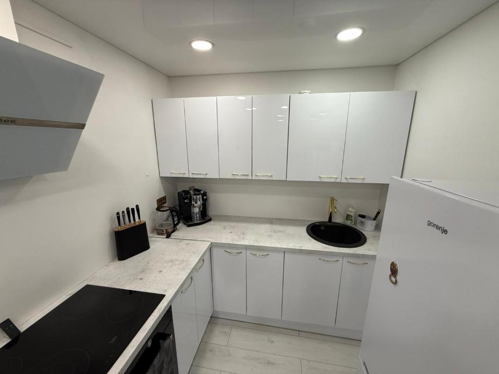 a white kitchen with a sink and a refrigerator at Welcome to Dovas Home in Anykščiai