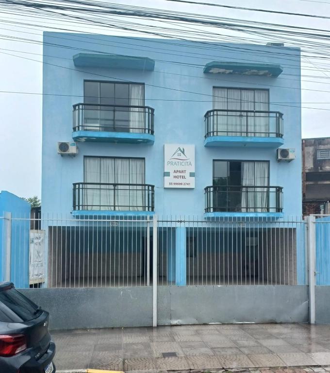 a blue building with a fence in front of it at Praticita Apart Hotel Ltda in São Gabriel
