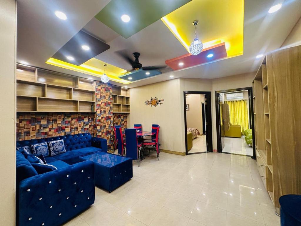 Una sala de estar con un sofá azul y una mesa. en Grand apartments, en Lahore