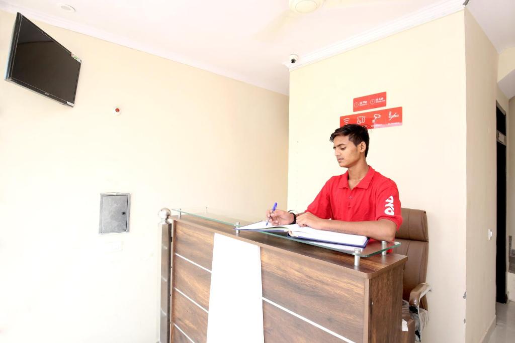 a man sitting at a desk in a room at Hotel O Sky in Zirakpur