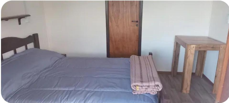 ein Schlafzimmer mit einem Bett und einem Holztisch in der Unterkunft Cabañitas surf bruskas in Miramar