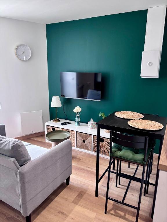 ein Wohnzimmer mit einem Sofa und einem Tisch mit einem TV in der Unterkunft Le Cocon Vert in Cognac