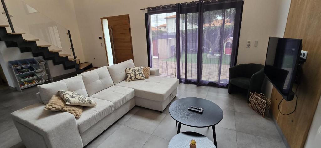 a living room with a white couch and a tv at Villa 4 chambres, jardin, Netflix in Canohès