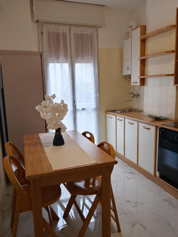 een keuken met een tafel met stoelen en een vaas met bloemen bij Il sorriso romagnolo in Misano Adriatico