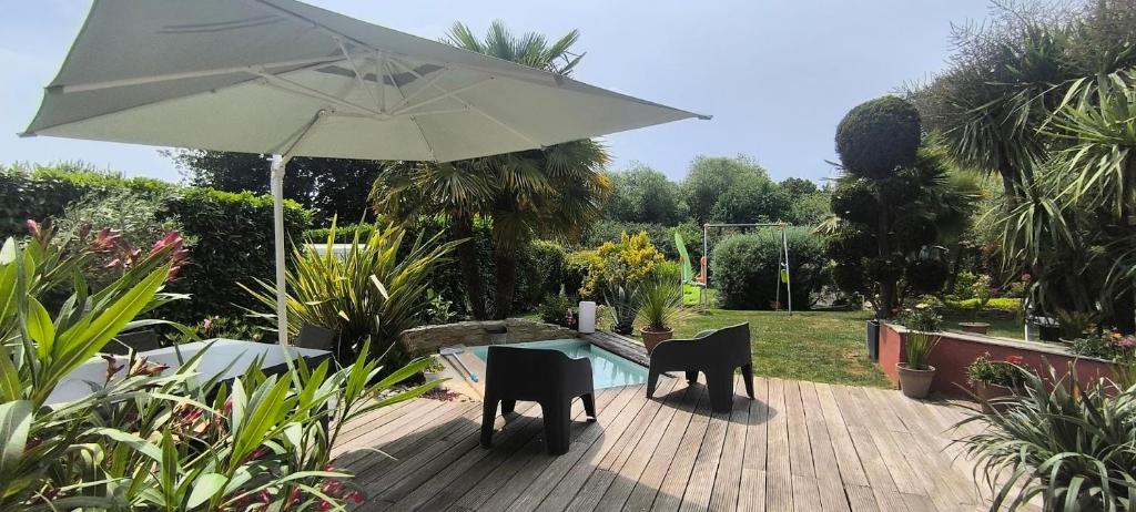 a table and chairs with an umbrella in a garden at Maison moderne 150 m2 à 15mn du centre ville in Aigné