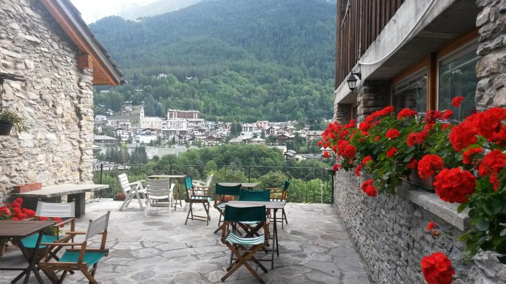 a patio with tables and chairs and red flowers at Hotel Dolonne in Courmayeur