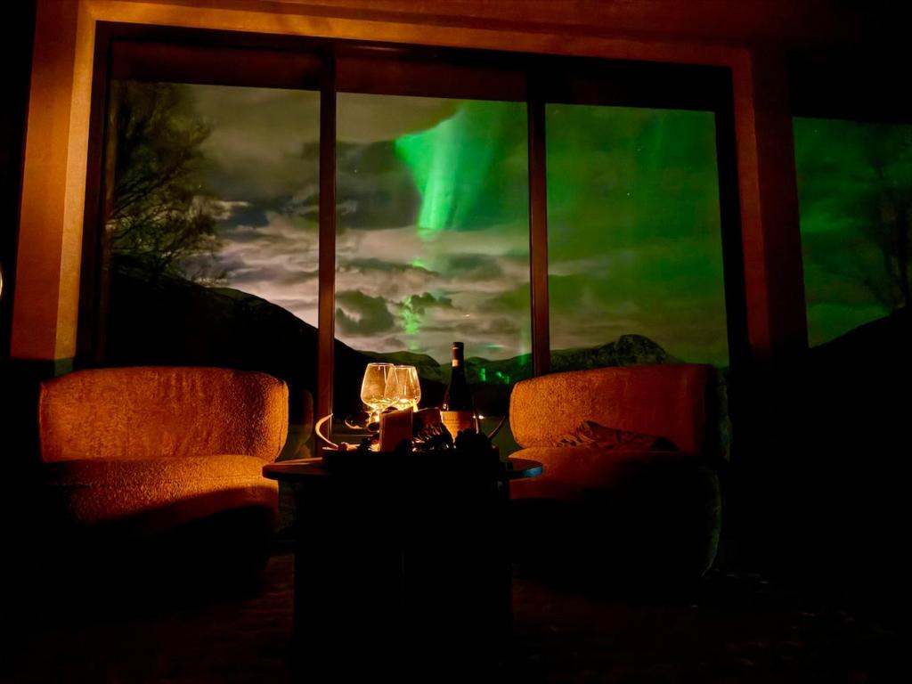a room with two chairs and a window with a green sky at Aurora Suite in Tromsø