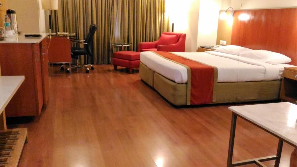 une chambre d'hôtel avec un lit et des chaises rouges dans l'établissement Taj Tristar, à Hyderabad