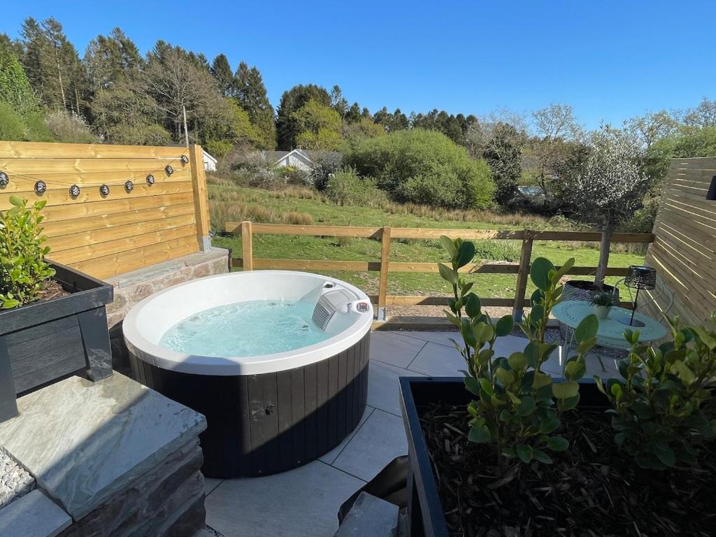 a hot tub sitting on top of a patio at The Summer House - Tiny Home with Hot Tub in Coity
