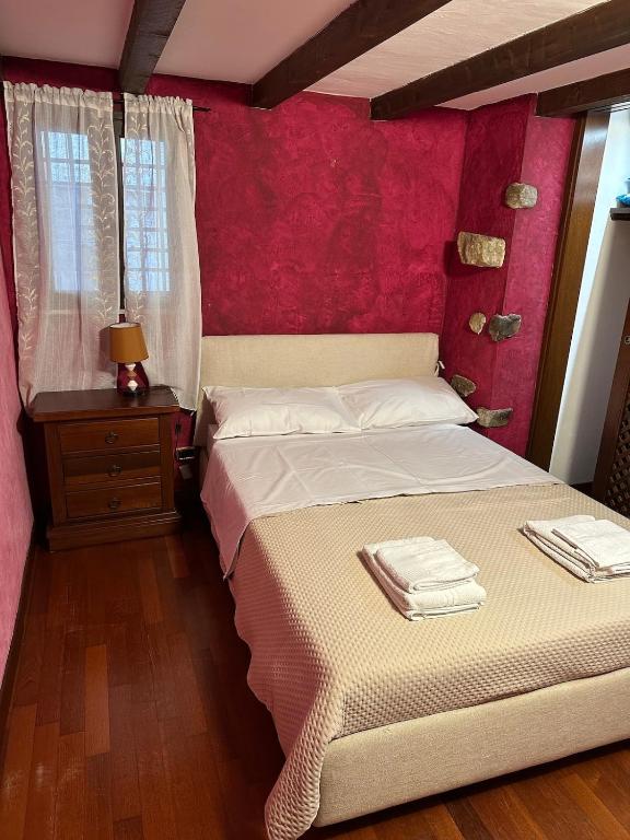 a bedroom with a bed with a red wall at Charme Rustico 70 mt from the beach, starlink in Cefalù
