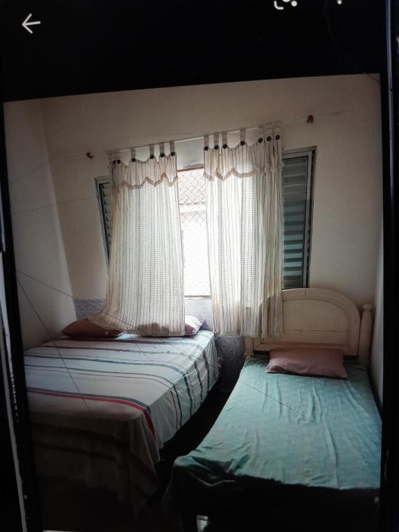 Una pequeña habitación con dos camas y una ventana. en Cantinho do aconchego, en Guarujá