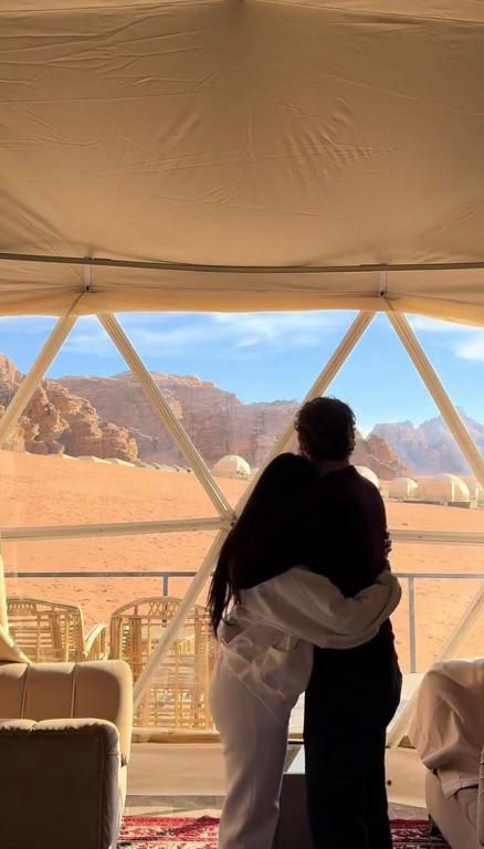 ワディ・ラムにあるMilky Way Luxury Campの窓の前で女性を抱きしめる男性