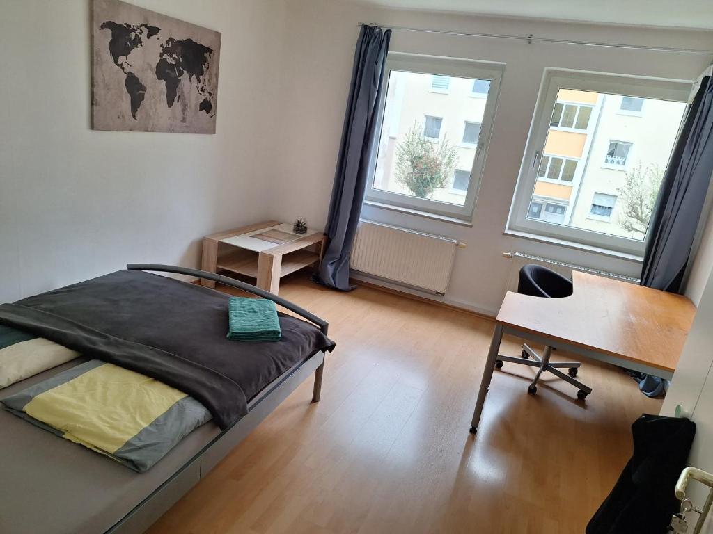 a bedroom with a bed and a desk and two windows at Big privat Zimmer 5 min walk from Railstation in Koblenz