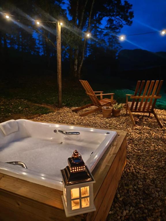 a bath tub with a candle in it with two chairs at Cabana liberdade 2 in Rio dos Cedros