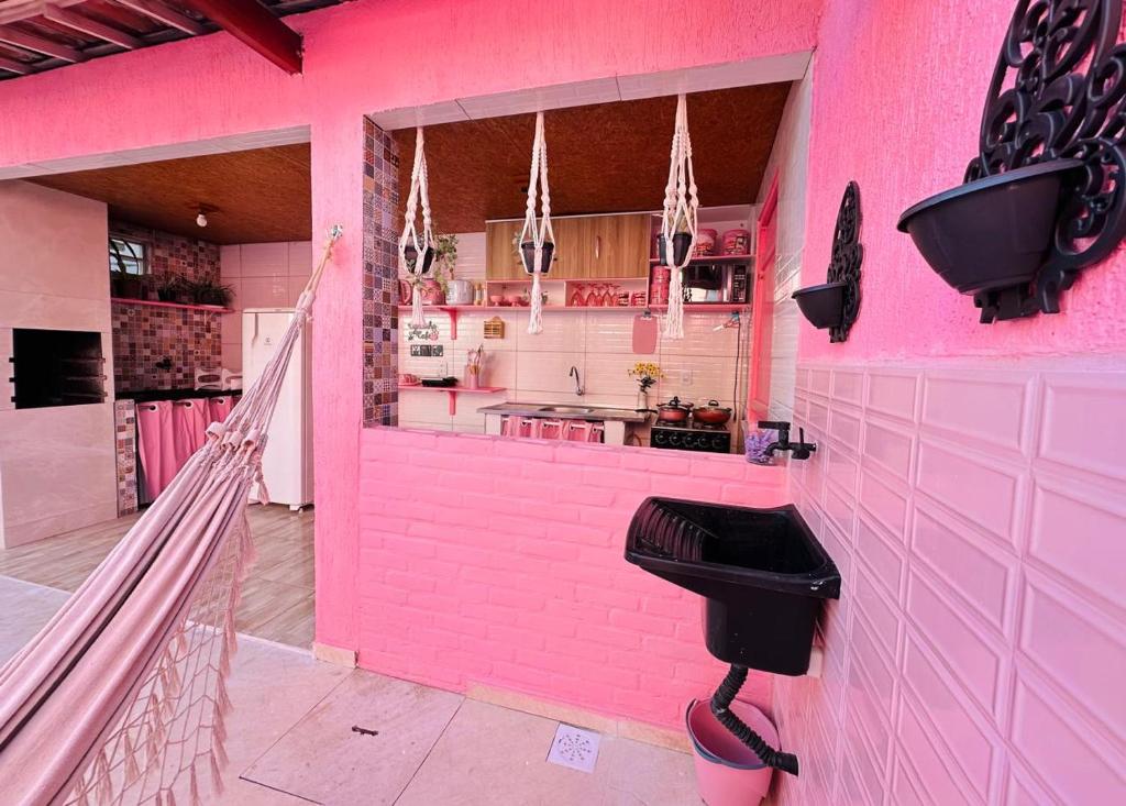 a pink bathroom with a black toilet in a pink wall at Na Casa Delas Jericoacoara in Jericoacoara