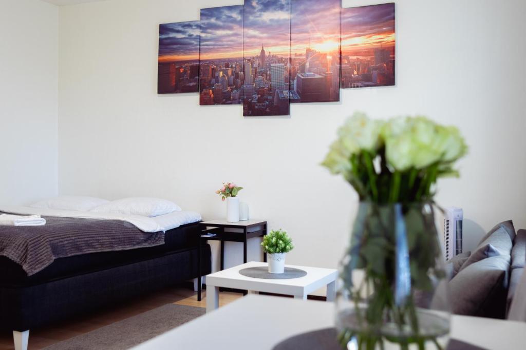 a room with a bed and a vase with flowers on a table at Railway&bus station studio, parking in Oulu