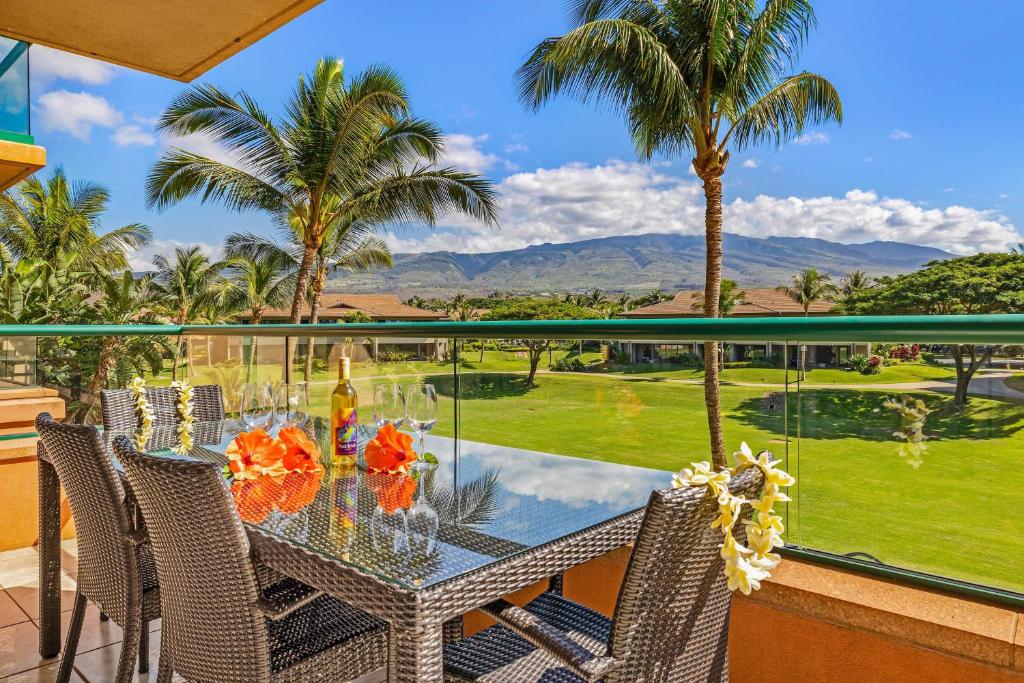 a table and chairs on a balcony with palm trees at Honua Kai Konea 206 in Lahaina