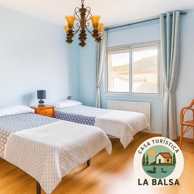 two beds in a room with a window at La Balsa in Matalebreras