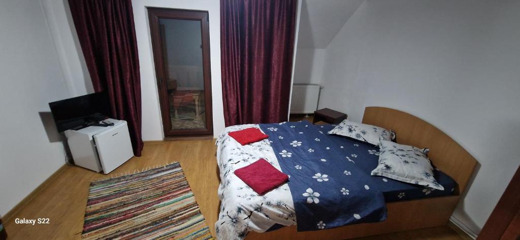 a bedroom with a bed with a blue comforter and pillows at La Neamțu in Văliug