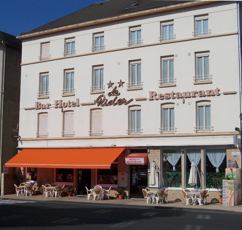 a large white building with tables and chairs on a street at Le Rider in Bort-les-Orgues