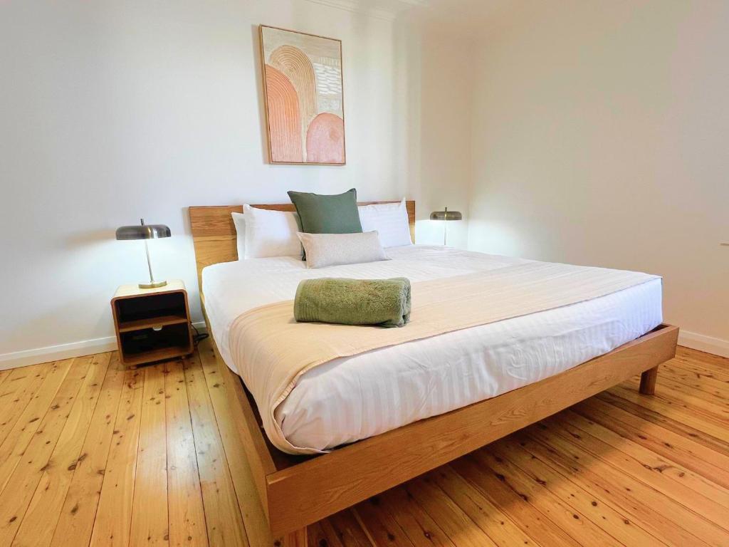 a large bed in a room with a wooden floor at Prickly Pear Stays in Merewether - Ranclaud St in Merewether