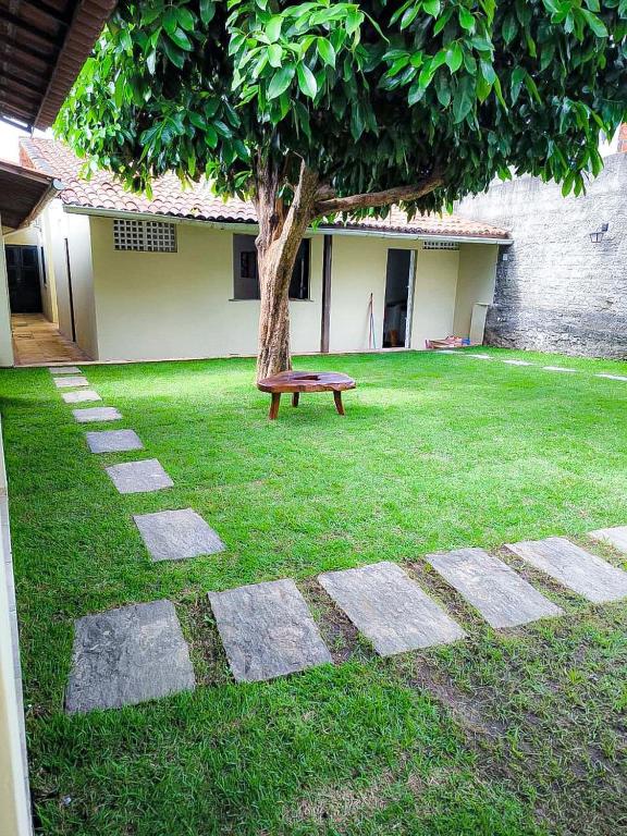 eine Bank im Gras neben einem Baum in der Unterkunft Casa Mahalo - no centro de Cumbuco in Caucaia