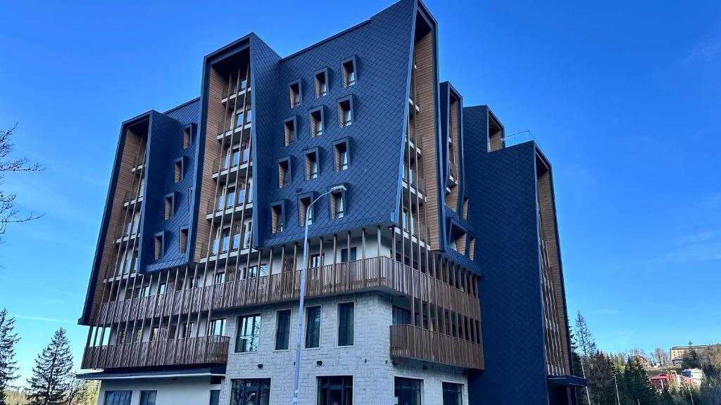 a tall building with a blue facade at Snowfall Luxury Suites Jahorina in Jahorina