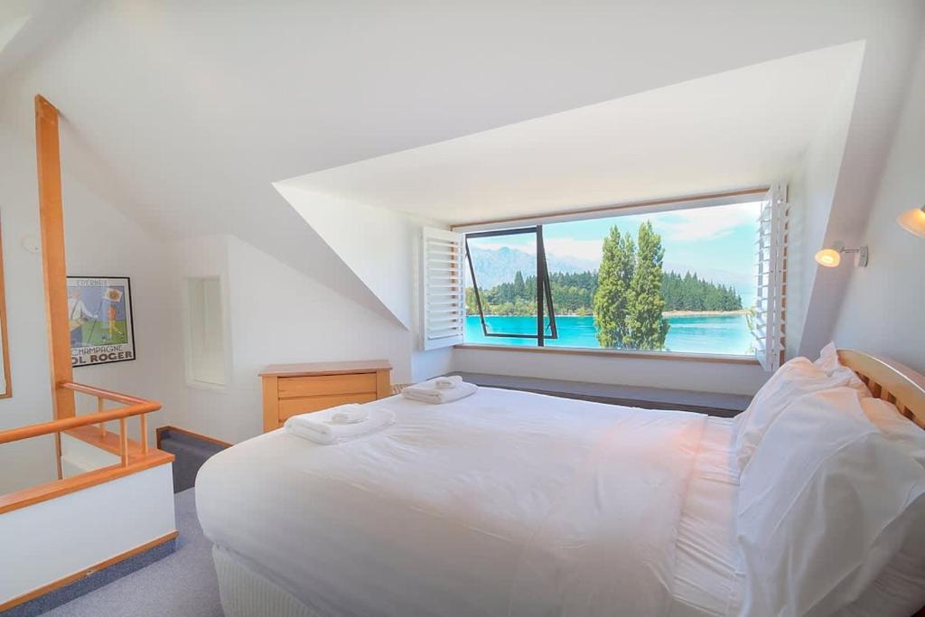 a bedroom with a white bed and a large window at The Lodges in Queenstown