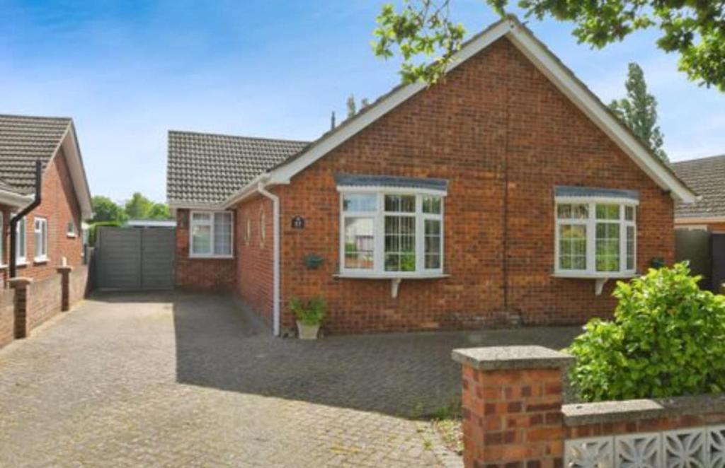 une maison en briques avec des fenêtres blanches et une allée dans l'établissement A lovely bungalow with 3 bedrooms and nice garden, à Boultham