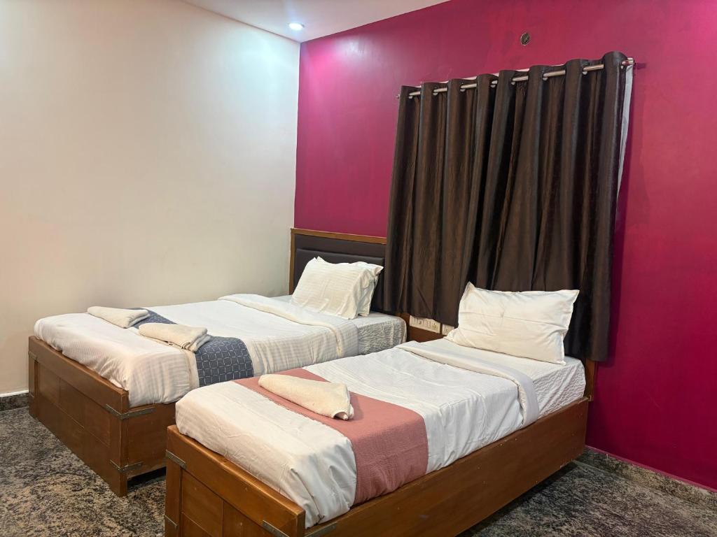 two beds in a room with pink walls at Heaven's Crest in Chennai
