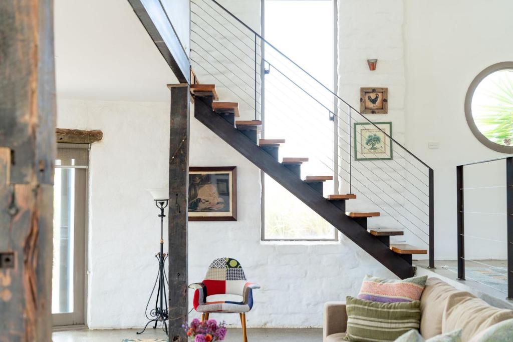 a living room with a couch and stairs at Lithia Guest House - Daylesford Region in Hepburn Springs