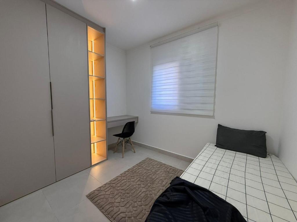 Apartamento Canto do Forte في برايا جراندي: غرفة نوم بها سرير ونافذة وكرسي