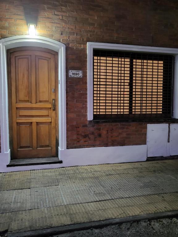 eine Holztür an einer Ziegelwand mit einem Fenster in der Unterkunft FLAT Fleming Martinez in Martínez